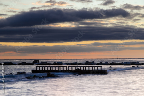 Amazing colourful sunrise seen over the Mediterranean Sea from Barceloneta Beach, which is located next to Barcelona's classic fishing quarter. It is the cities oldest and best-loved beach and gives w