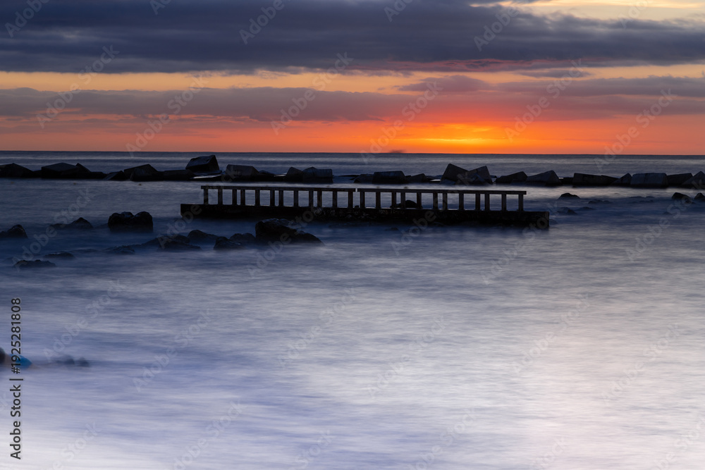 Fototapeta premium Amazing colourful sunrise seen over the Mediterranean Sea from Barceloneta Beach, which is located next to Barcelona's classic fishing quarter. It is the cities oldest and best-loved beach and gives w