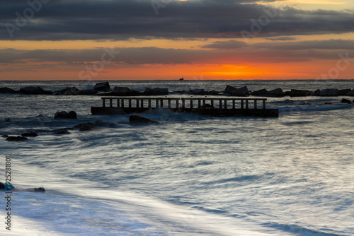 Amazing colourful sunrise seen over the Mediterranean Sea from Barceloneta Beach, which is located next to Barcelona's classic fishing quarter. It is the cities oldest and best-loved beach and gives w