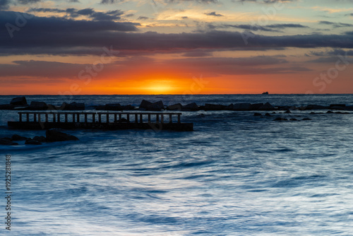 Amazing colourful sunrise seen over the Mediterranean Sea from Barceloneta Beach, which is located next to Barcelona's classic fishing quarter. It is the cities oldest and best-loved beach and gives w