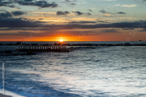 Amazing colourful sunrise seen over the Mediterranean Sea from Barceloneta Beach, which is located next to Barcelona's classic fishing quarter. It is the cities oldest and best-loved beach and gives w