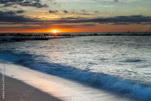 Amazing colourful sunrise seen over the Mediterranean Sea from Barceloneta Beach, which is located next to Barcelona's classic fishing quarter. It is the cities oldest and best-loved beach and gives w