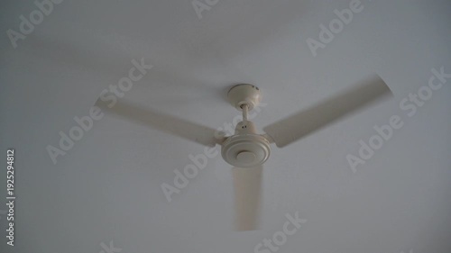 Ceiling fan spinning on a white ceiling, household ventilation and air cooling system in a modern interior