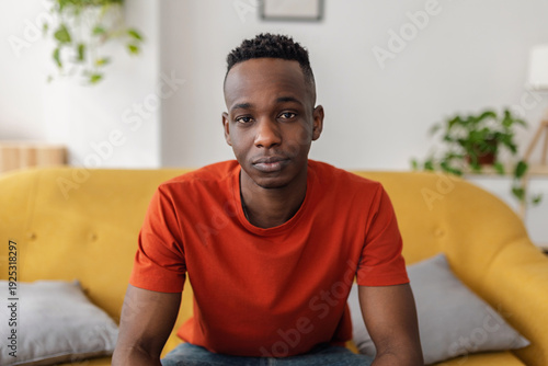 Fotografía Confident African man sitting on sofa looking directly at the camera with a serious and thoughtful expression