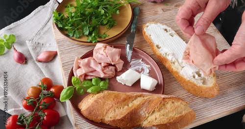 Anonymous person prepares sandwich with cheese, basil, and mortadella in kitchen. Italian cuisine, high-quality farm-to-table ingredients.