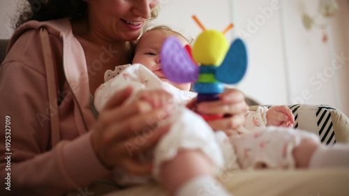 Wallpaper Mural Smiling mother playing with her baby using a colorful toy at home Torontodigital.ca