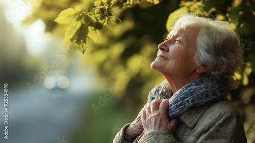 Serene Reflection: An older woman with silver hair, her face upturned towards the soft sunlight, embraces the tranquility of nature, a moment of peaceful contemplation.