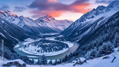 Snowy mountain range valley with winding river below at dawn or dusk