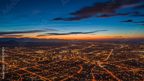 Cityscape at twilight with illuminated streets and mountains against colorful sky