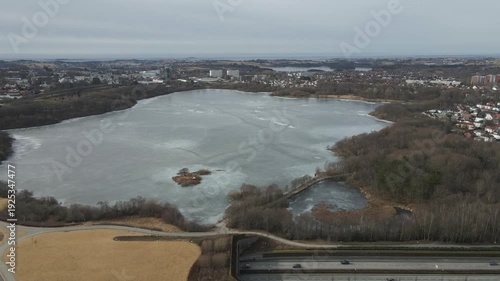 Wallpaper Mural Aerial drone footage showing a frozen lake captured at midday. The scene features ice-covered water surfaces under direct daylight, highlighting textures, open surroundings, and clear winter condition Torontodigital.ca
