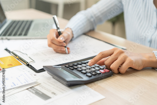 Fotografie Stressed person asian young employee woman hand using calculator to calculate expenses of monthly and checking expenses from bill, receipt on table at home