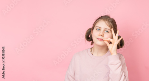 Принти на полотні Cute preteen girl making zipper mouth gesture on pink background.