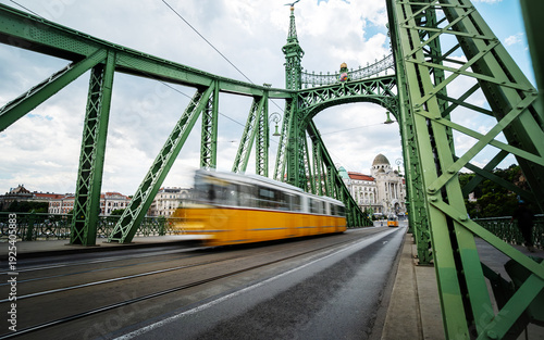 Retro Yellow Tram Rushes With Motion Blur Effect, Driving Fast By Freedom Bridge In Budapest