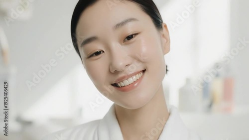 Asian woman smiling in a white lab coat in a lab with blurred background
