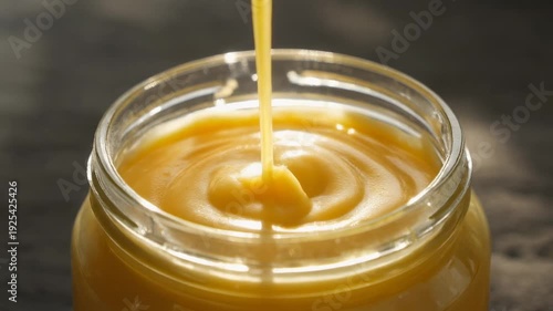 Golden Ghee Pouring into Glass Jar Backlit by Natural Sunlight