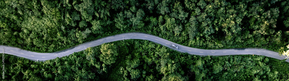 Fototapeta premium Aerial forest road with car creating abstract background for electric vehicle, ESG, sustainability and green investment business concepts.