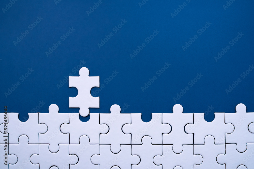 Fototapeta premium White puzzle pieces connecting to form a final missing section