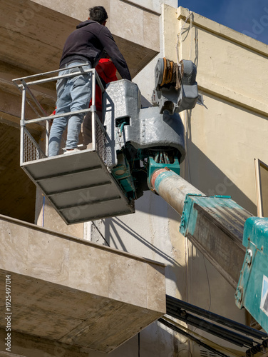Workers on aerial lift repairing building facade