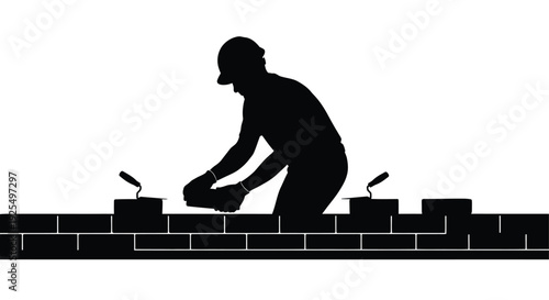 Construction worker laying bricks on a wall a stark black silhouette