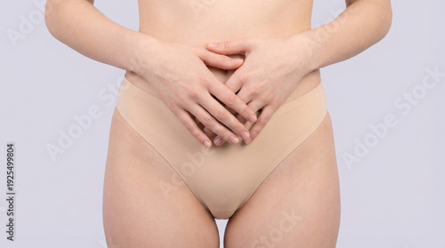 Wallpaper Mural Person wearing beige underwear holds their hands clasped together over their lower abdomen area against a light gray backdrop. Torontodigital.ca