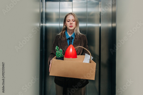 Woman standing in elevator with box after being fired from job