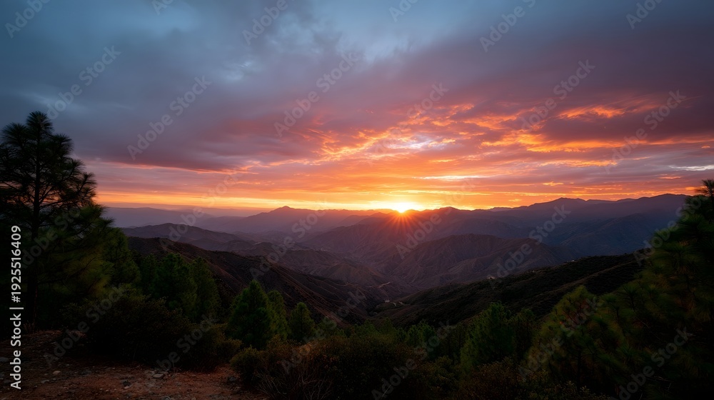 Obraz premium Vibrant sunset over dramatic mountain range with colorful clouds and sun rays
