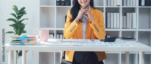Radiant Businesswoman at Work: A poised businesswoman, exuding confidence and a warm smile, is seated at her modern desk, ready to embark on another successful day of work.