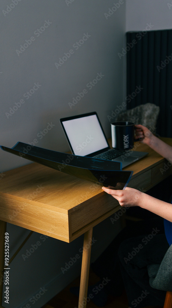 Naklejka premium Person working at a wooden desk with a laptop and a mug that says work