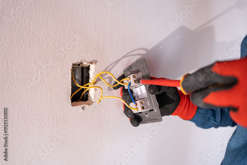Obraz na plátně Close-up of an experienced electrician's hands repairing a breaker with a screwd