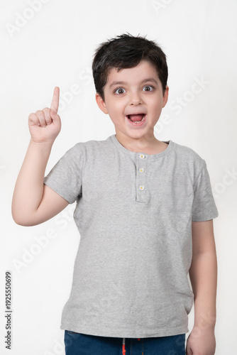 Excited child with good expressions pointing up with white background.