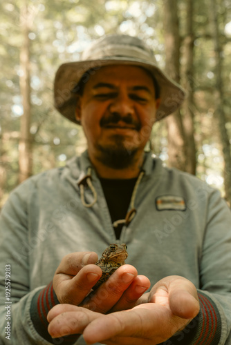 Male biologist studying frog outdoors in natural environment