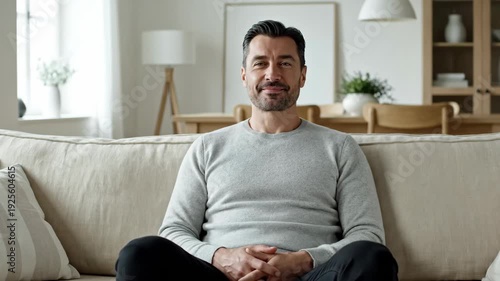 Marketer thinking in modern office with cozy couch, smiling businessman sitting relaxed on sofa in bright room. Marketer office space designed for comfort and productivity in professional environment.