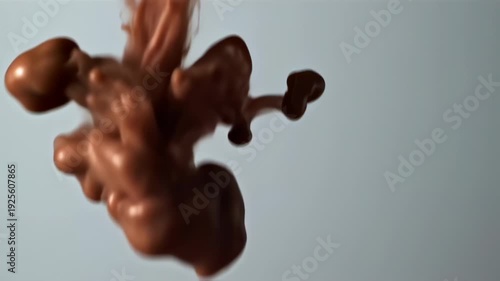 Fluid orange substance swirls through a light-gray background, with blurred shapes and delicate tendrils