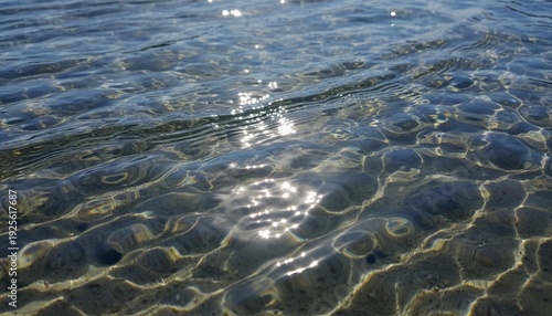 Sunlight reflects brightly off the ripples of shallow, clear water illuminating the textured sand bed below.