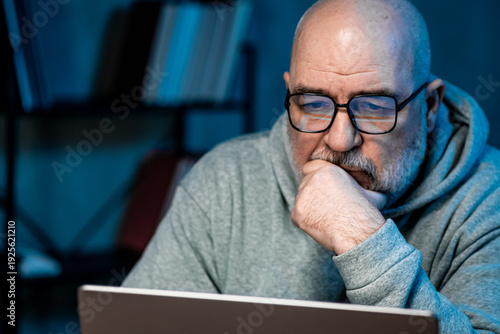 Concentrated professional in glasses reviewing financial metrics on computer screen after office hours. Digital business workflow concept.
