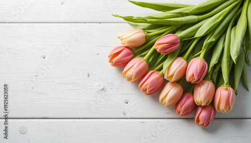 Bouquet of pink tulips with green leaves on a white wooden table
