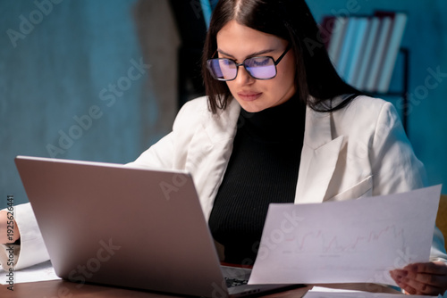 Professional businesswoman focused on her work at an office desk while reviewing important paperwork. Corporate workflow, responsibility, office productivity concept.

