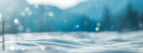 Snowy landscape with blurry trees and mountains in background during snowfall