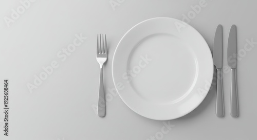 Minimal table setting with empty white plate and cutlery on light background