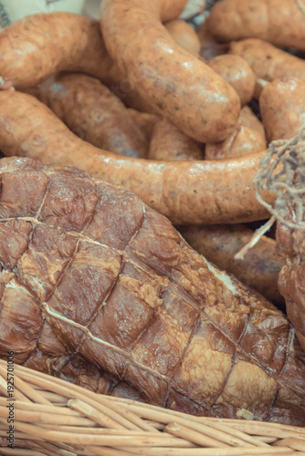 Fresh prepared smoked hams with spices in wicker basket on market stall