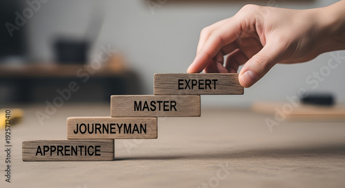 Hand placing an expert level wooden block on a stack representing career progression and skill development