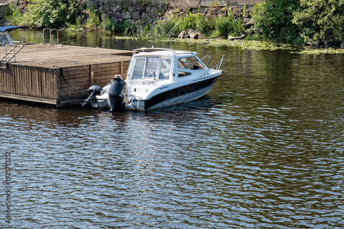 Boat docked by a wooden pier on a calm river during the afternoon sunshine