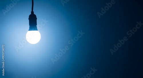 A single glowing light bulb hanging in the dark