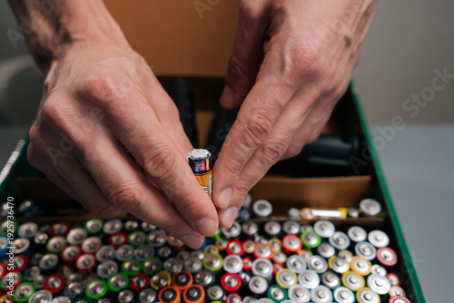 Tableau sur toile Hands holding damaged alkaline battery with white corrosion, preparing for prope