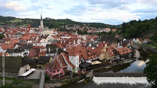Panoramic Sunset City View of Cesky Krumlov during sunset. The footage captures the historic castle, the iconic round tower, and the red-roofed medieval houses nestled along the Vltava river.