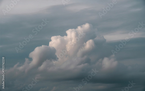 Dramatic white cumulus cloud against a dark moody sky before a storm.