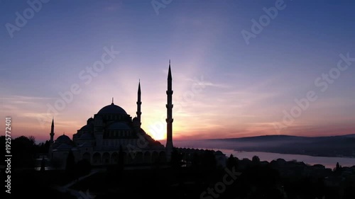 Majestic mosque silhouette at sunrise, with vibrant sky and misty waters, symbolizing peace and spirituality.