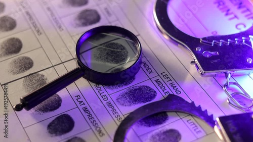 Forensic identification concept with fingerprint cards, handcuffs and police light.