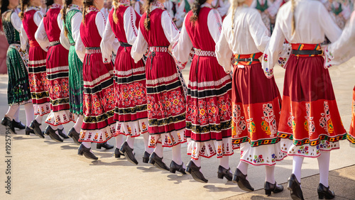 Fotografía Women in traditional embroidered folk dresses dancing in synchronized movement at cultural festival