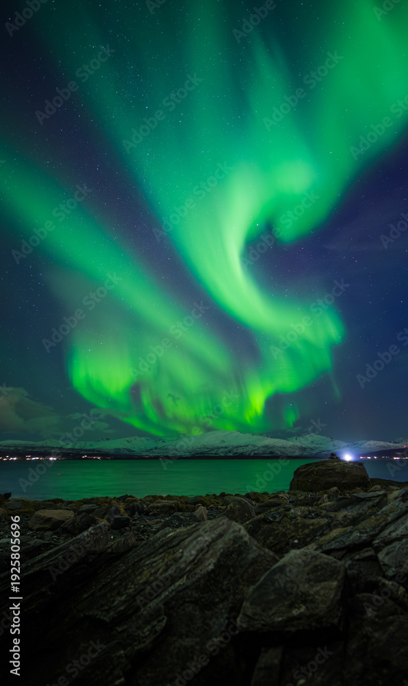 Naklejka premium l'aurora boreale si mostra sul mare, vista dalla città di tromso